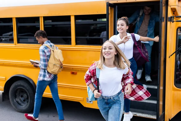 Feliz multiétnico adolescente estudiosos correndo para fora ônibus escolar — Fotografia de Stock