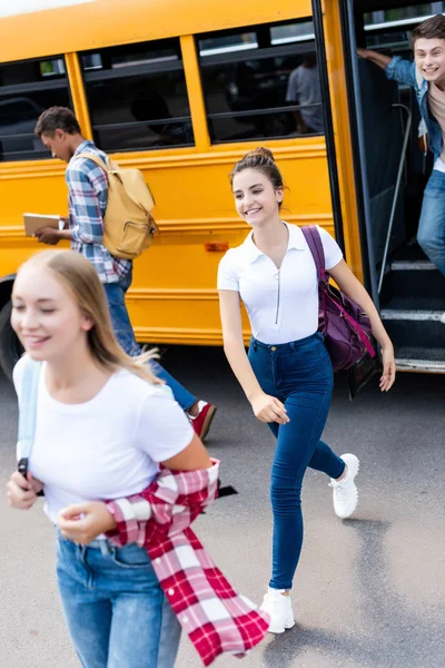 Group of multiethnic teen scholars running out school bus — Stock Photo