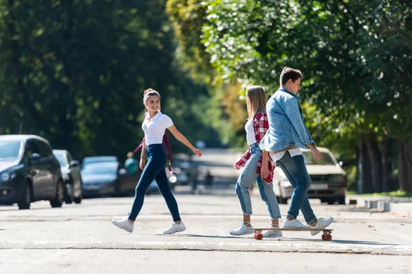 Vista lateral de estudiantes adolescentes cruzando la carretera - foto de stock