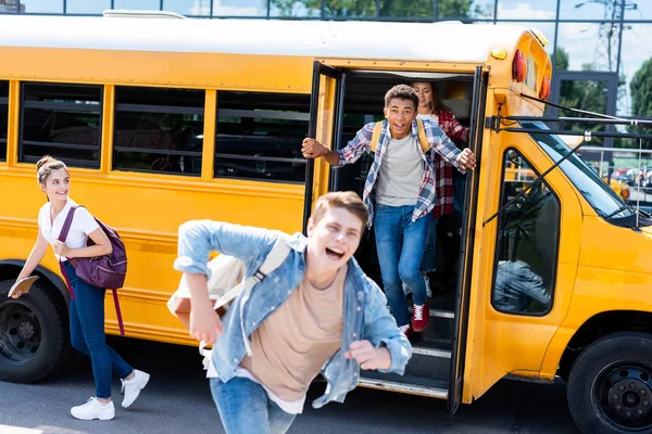 Grupo de adolescentes estudiosos correndo para fora ônibus escolar e gritando — Fotografia de Stock