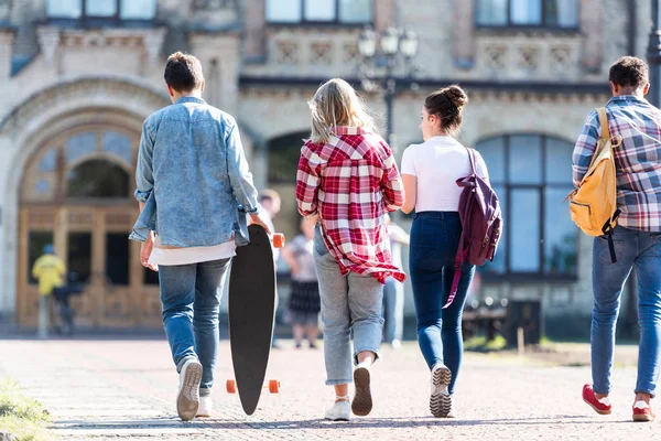 Rückansicht einer Gruppe Jugendlicher, die am Schulgebäude spazieren geht — Stockfoto