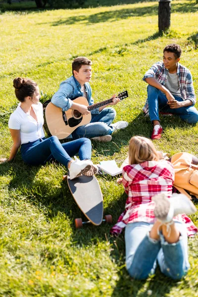 Gruppe von Teenagern verbringt Zeit miteinander und hört Gitarrenlieder — Stockfoto