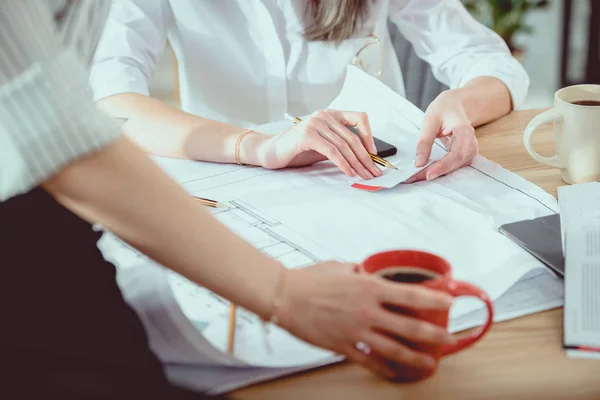 Plan recadré de jeunes architectes travaillant avec un plan directeur et buvant du café — Photo de stock