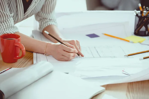 Cropped shot of businesswoman using pencil during work with blueprints — Stock Photo