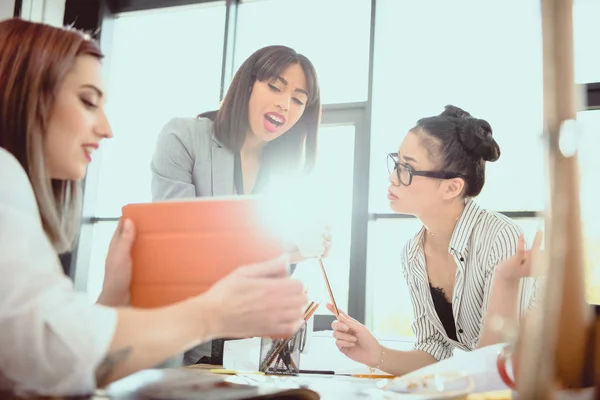 Young businesswomen working together and using digital tablet in office — Stock Photo