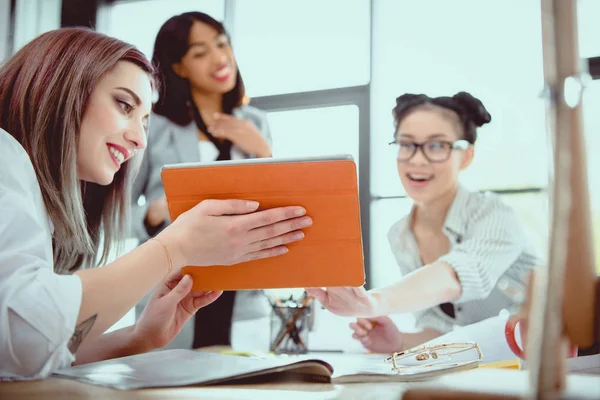 Young businesswomen working together and using digital tablet in office — Stock Photo