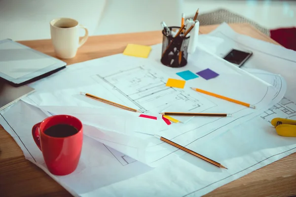 Vista de primer plano de los planos con suministros de oficina y tazas de café en la mesa - foto de stock