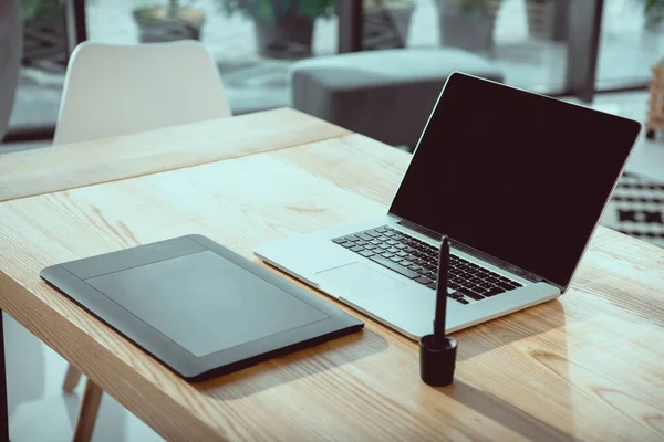 Laptop with blank screen and graphics tablet on wooden tabletop at office — Stock Photo