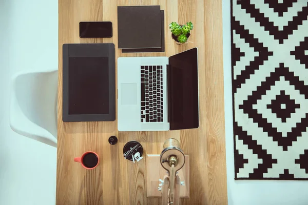 Vue du dessus de l'ordinateur portable avec tablette graphique et smartphone sur table en bois au bureau — Photo de stock