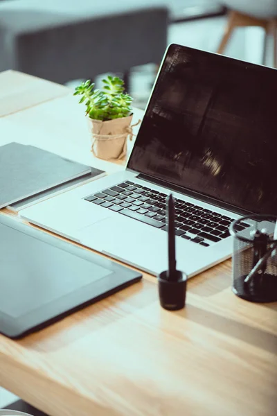 Close up of laptop with graphics tablet on wooden tabletop at office — Stock Photo