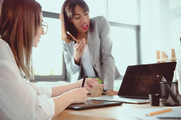 Jóvenes diseñadores multiétnicos que trabajan con dispositivos digitales en la oficina - foto de stock