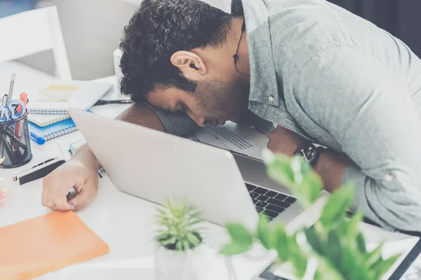 Gelegenheitsunternehmer schläft auf dem Tisch neben Laptop im modernen Büro — Stockfoto