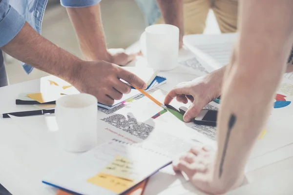 Cropped shot of businessmen pointing at diagrams and working on new project at office — Stock Photo