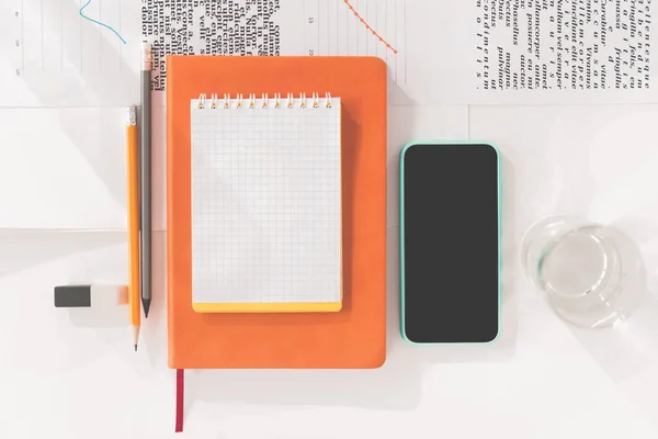 Top view of smartphone with blank screen, notebooks and pencils at workplace — Stock Photo