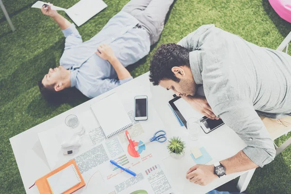 Young businessmen sleeping on the table and green grass carpet at modern office, business teamwork — Stock Photo