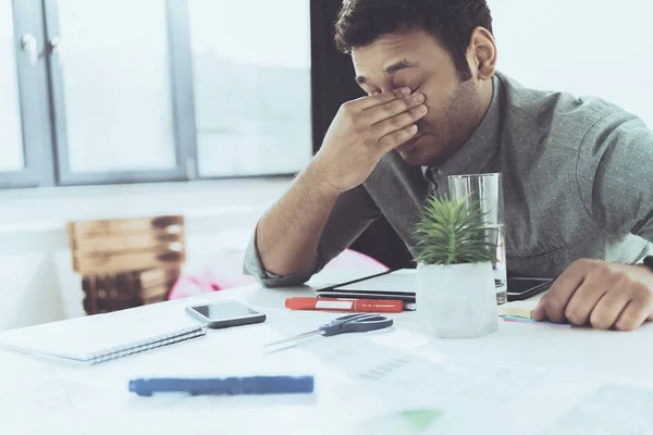 Joven cansado hombre de negocios casual sentado a la mesa en la oficina, establecimiento de negocios - foto de stock