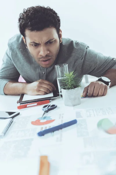 Young tired casual businessman sitting at table in office, business establishment — Stock Photo