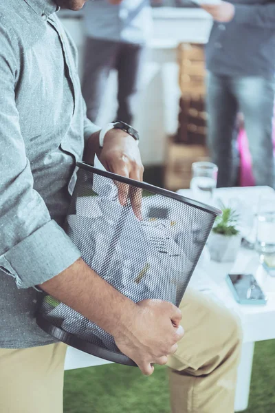 Partial view of businessman holding trash bucket with papers, business teamwork — Stock Photo