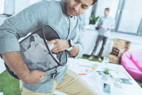 Vista lateral del empresario pensativo sosteniendo cubo de basura con papeles, trabajo en equipo de negocios - foto de stock