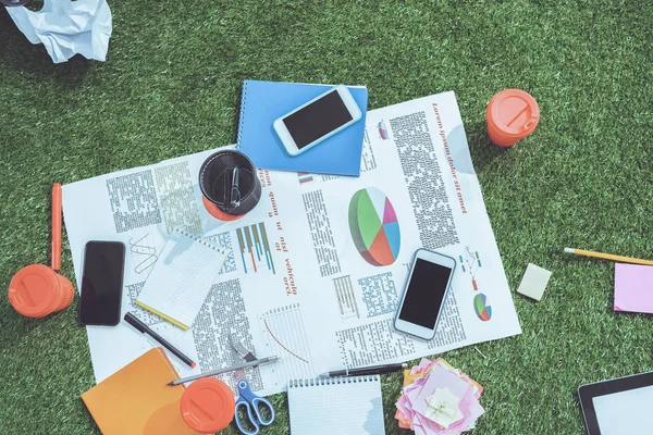 Heap of business objects and office supplies laying on green grass carpet at office, business establishment — Stock Photo