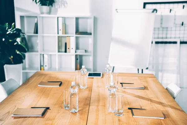 Empty conference hall with bottles of water and notebooks — Stock Photo