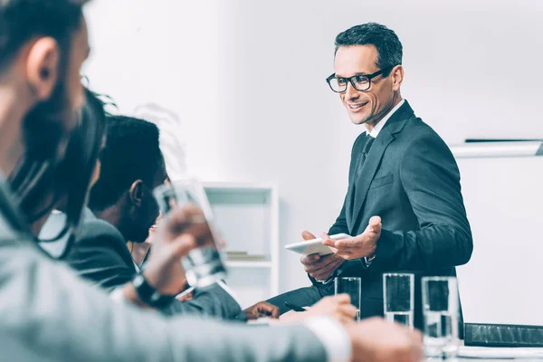 Schöner Geschäftsmann mittleren Alters im Gespräch mit multirassischen Partnern im Konferenzsaal — Stockfoto