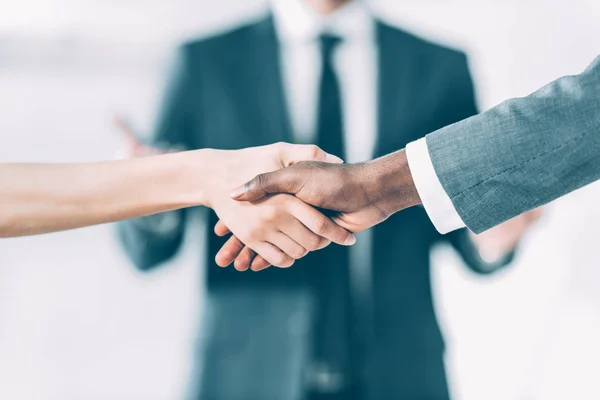 Tiro recortado de socios comerciales multiculturales masculinos y femeninos estrechando la mano - foto de stock