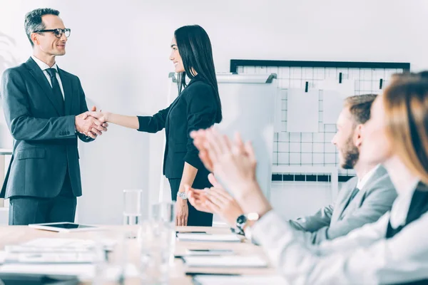 Chef schüttelt asiatische Managerin im Konferenzsaal die Hand, während Kollegen klatschen — Stockfoto