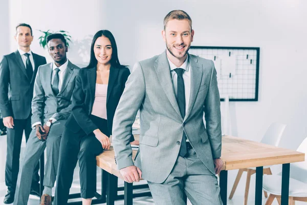 Felices empresarios multiculturales exitosos sentados en la mesa en la oficina - foto de stock