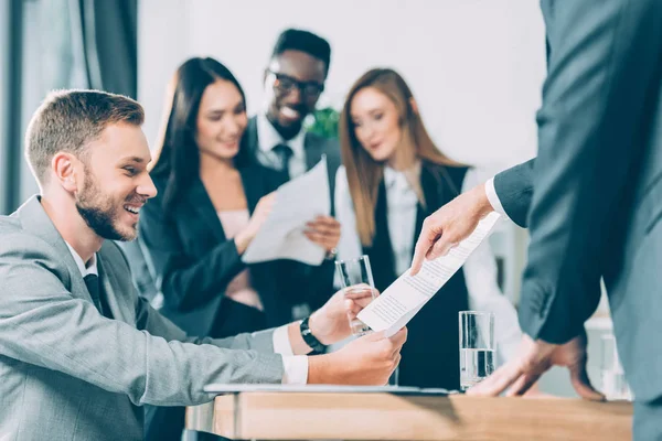 Empresarios multirraciales explorando documentos en la oficina moderna - foto de stock