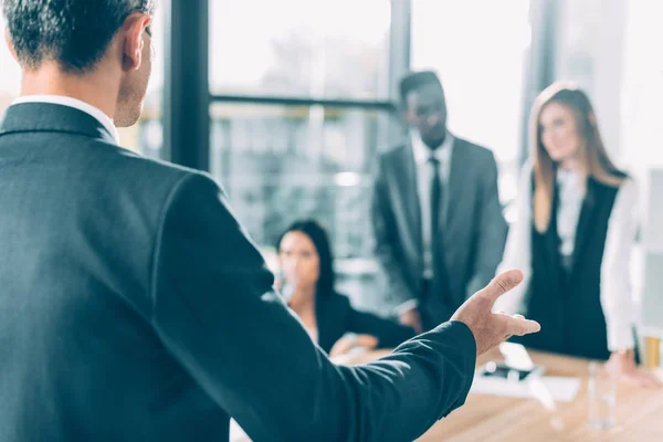 Cropped shot of businessman talking to multiracial partners — Stock Photo