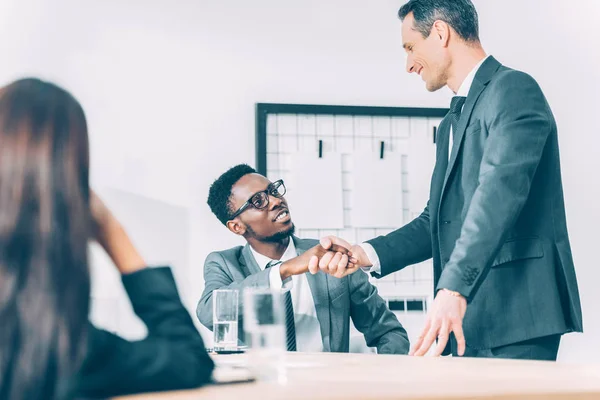 Homens de negócios multiétnicos bonitos apertando as mãos no escritório moderno — Fotografia de Stock