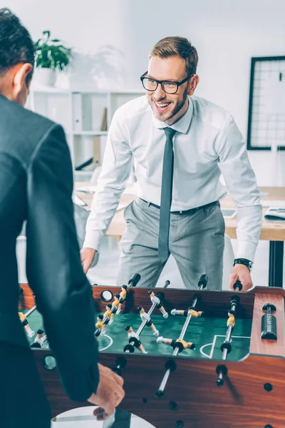 Uomini d'affari che giocano a calcio balilla in ufficio moderno — Foto stock