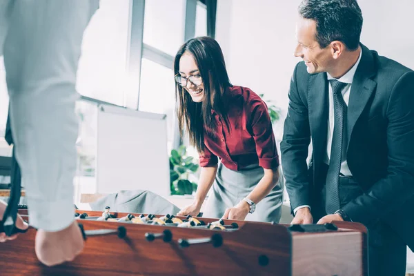 Empresários multirraciais felizes jogando futebol de mesa no escritório moderno — Fotografia de Stock