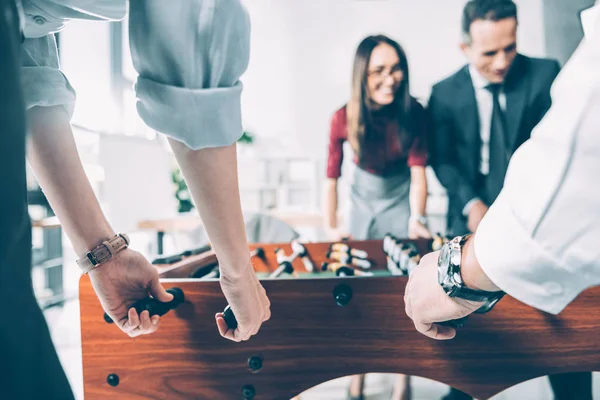 Close-up shot of multiracial businesspeople playing table football in modern office — Stock Photo