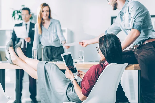 Joven asiático mujer de negocios utilizando tableta en conferencia sala con borrosa colegas en fondo - foto de stock