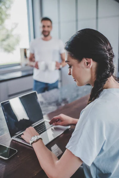 Side view of girlfriend using laptop in kitchen — Stock Photo