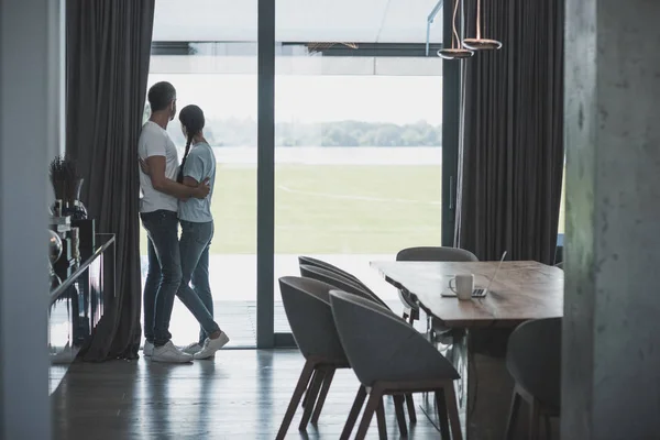 Vista trasera del hombre adulto abrazando novia en casa - foto de stock