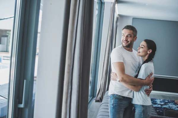 Lächelnder erwachsener Mann umarmt attraktive Freundin zu Hause — Stockfoto
