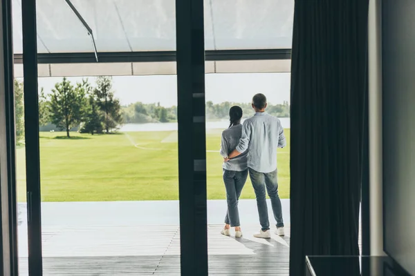 Back view of man embracing girlfriend at porch of country house — Stock Photo