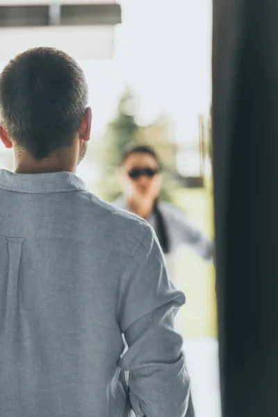 Vista trasera del hombre caminando a su novia esperándolo en casa - foto de stock