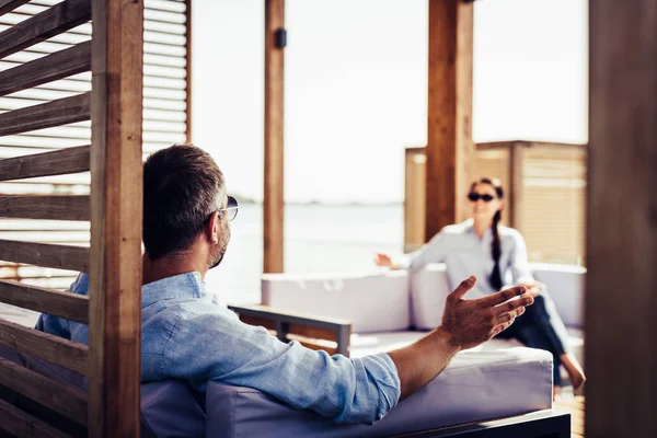 Rear view of man in sunglasses gesturing by hand and talking to girlfriend at country house — Stock Photo