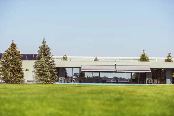 Surface level of green lawn and modern cottage under blue clear sky — Stock Photo