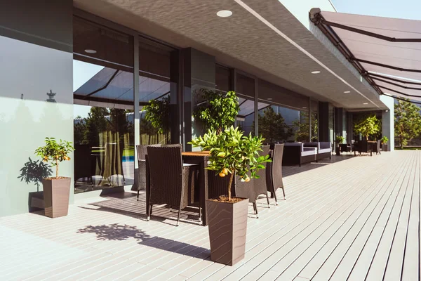 Véranda de maison de campagne moderne avec de petits arbres, chaises et tables — Photo de stock