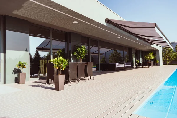 Schwimmbad und Veranda eines modernen Landhauses mit kleinen Bäumen, Stühlen und Tischen — Stockfoto