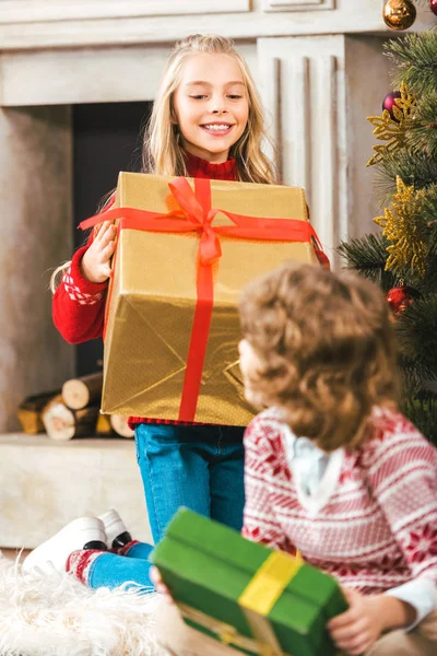 Glückliche kleine Geschwister mit Geschenkboxen, die Weihnachten feiern — Stockfoto