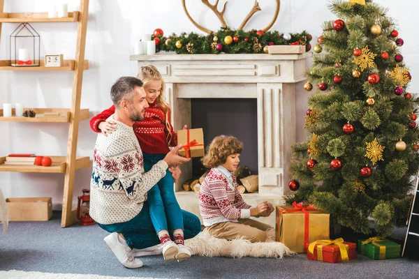 Glücklicher Vater und Kinder nehmen Geschenke unter dem Weihnachtsbaum entgegen — Stockfoto
