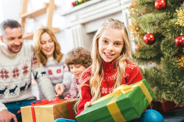 Linda criança com presente passando tempo com o irmão e os pais no Natal em casa — Fotografia de Stock