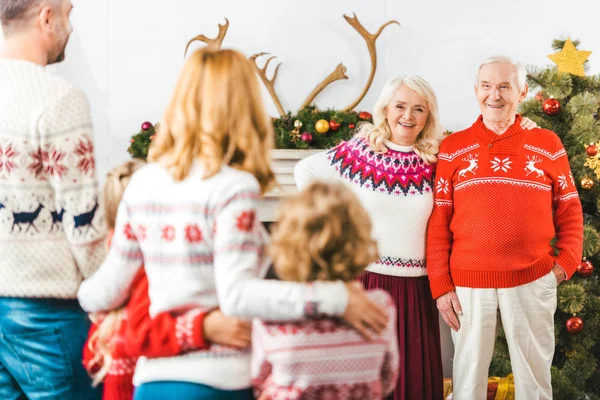 Grands-parents regardant leurs enfants à la maison pendant Noël — Photo de stock