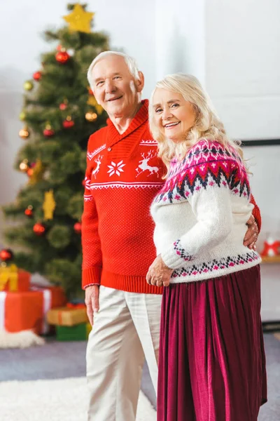 Happy senior couple in christmas sweaters looking at camera — Stock Photo